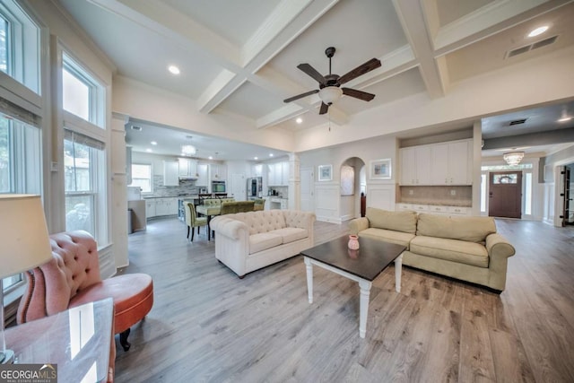 living area featuring visible vents, ceiling fan, beamed ceiling, coffered ceiling, and ornate columns