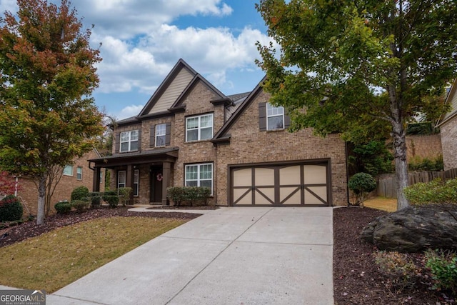 craftsman-style home with a garage, brick siding, driveway, and fence