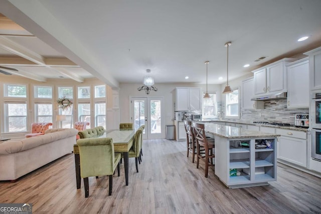 dining space with beam ceiling, visible vents, and light wood-type flooring