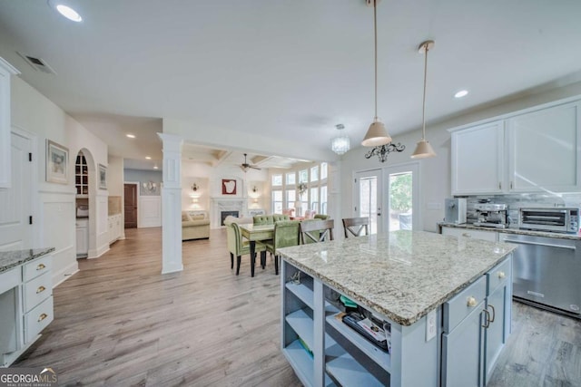 kitchen featuring visible vents, light wood finished floors, a fireplace, dishwasher, and tasteful backsplash