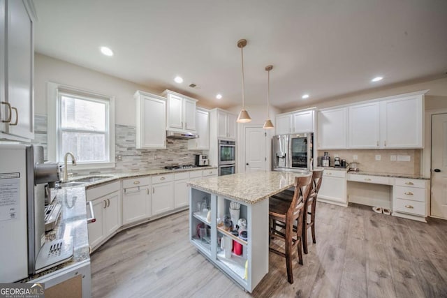 kitchen with a breakfast bar, light wood-style floors, white cabinets, stainless steel appliances, and a sink