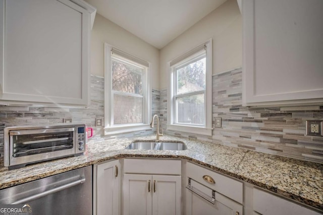 kitchen featuring white cabinetry, a toaster, a sink, dishwasher, and backsplash