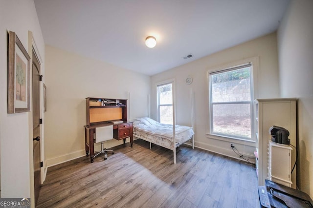 bedroom with wood finished floors, visible vents, and baseboards