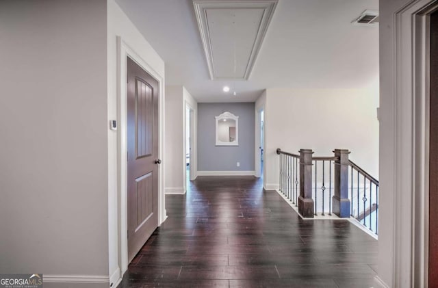 hall with visible vents, baseboards, attic access, an upstairs landing, and wood finished floors