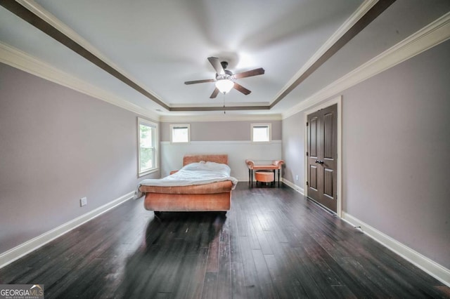 bedroom featuring a tray ceiling, crown molding, dark wood-type flooring, and baseboards