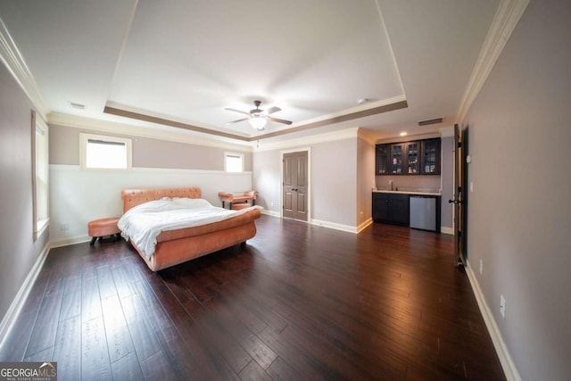 bedroom with indoor wet bar, crown molding, dark wood-type flooring, and a tray ceiling