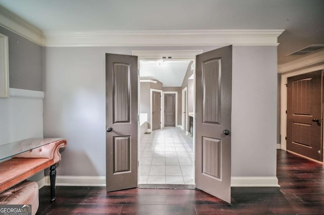 hall with visible vents, wood finished floors, baseboards, and ornamental molding