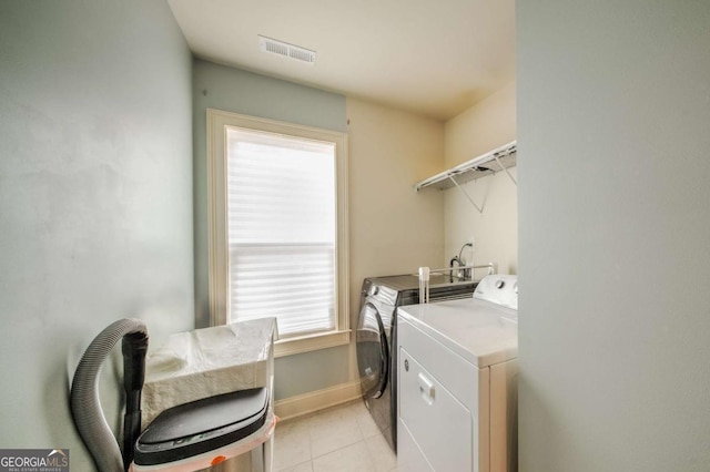 laundry area with light tile patterned floors, baseboards, visible vents, washing machine and clothes dryer, and laundry area