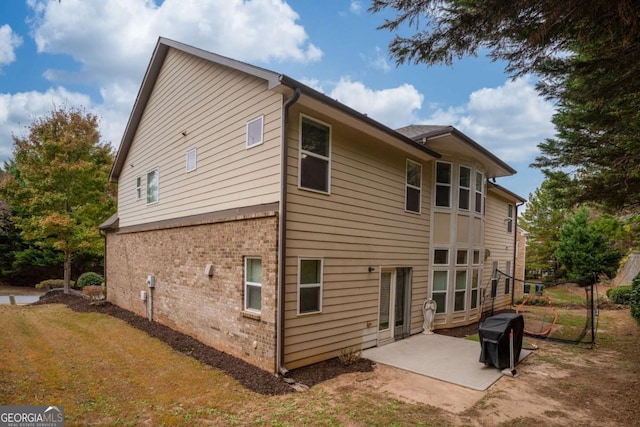 rear view of property featuring brick siding and a patio area