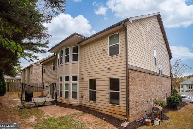 rear view of house featuring a patio area, brick siding, and fence