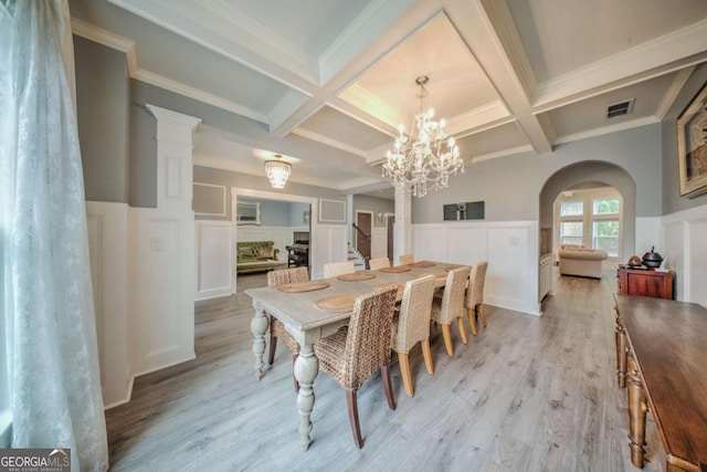 dining area with beamed ceiling, light wood-style floors, and visible vents