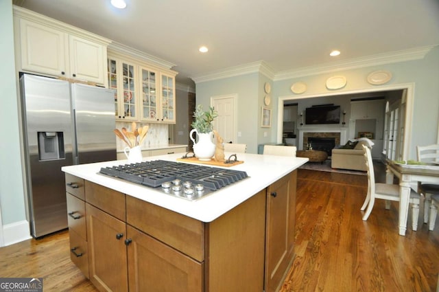 kitchen with ornamental molding, stainless steel appliances, a fireplace, glass insert cabinets, and dark wood-style flooring