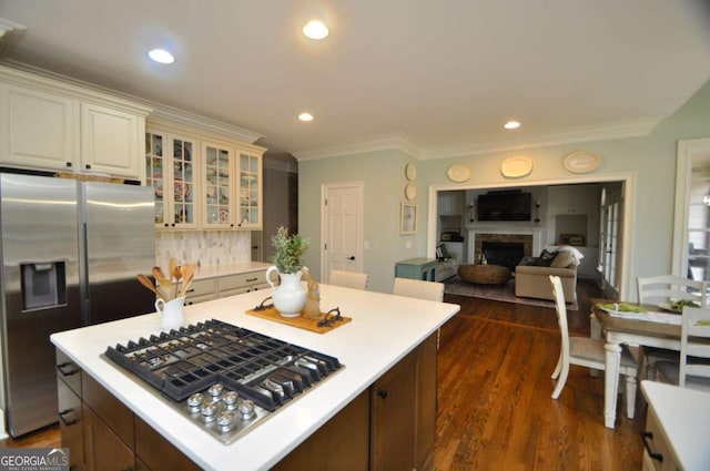 kitchen featuring glass insert cabinets, light countertops, a fireplace, stainless steel appliances, and dark wood-style flooring