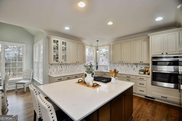 kitchen featuring decorative backsplash, light countertops, a healthy amount of sunlight, and stainless steel appliances