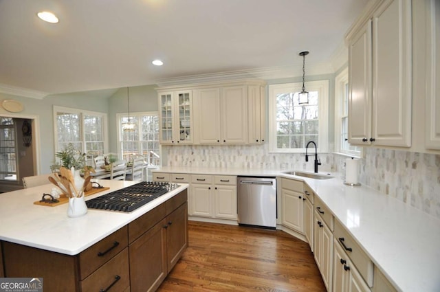 kitchen with a kitchen island, a sink, appliances with stainless steel finishes, decorative light fixtures, and backsplash