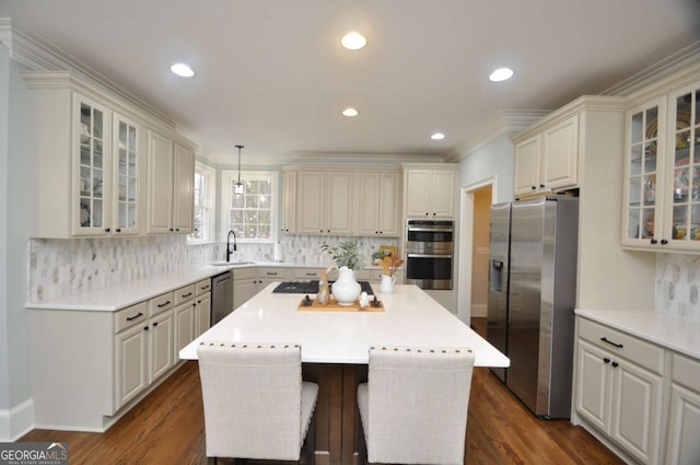 kitchen with a sink, dark wood finished floors, a center island, appliances with stainless steel finishes, and light countertops