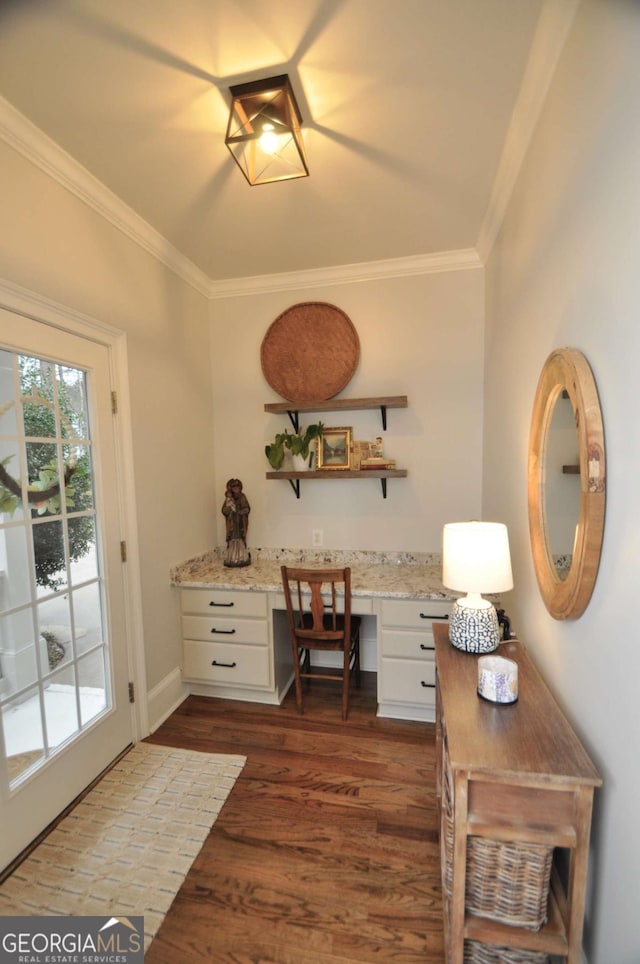 interior space featuring crown molding, built in study area, dark wood-type flooring, and baseboards