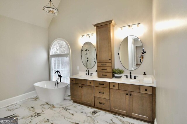 full bath with a freestanding tub, marble finish floor, baseboards, and a sink