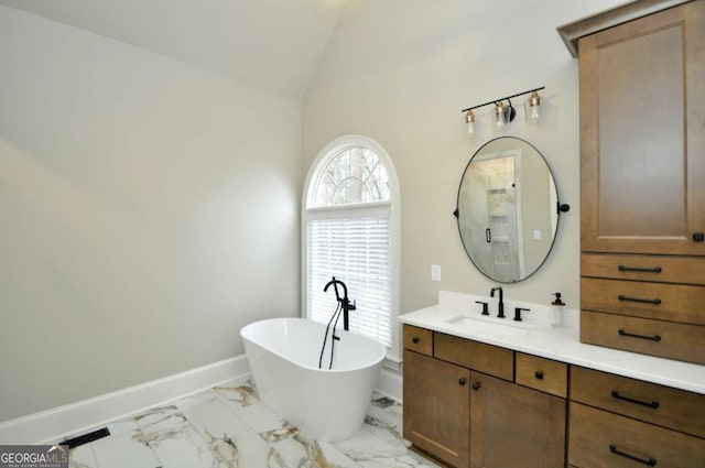 bathroom with vanity, baseboards, a freestanding bath, vaulted ceiling, and marble finish floor