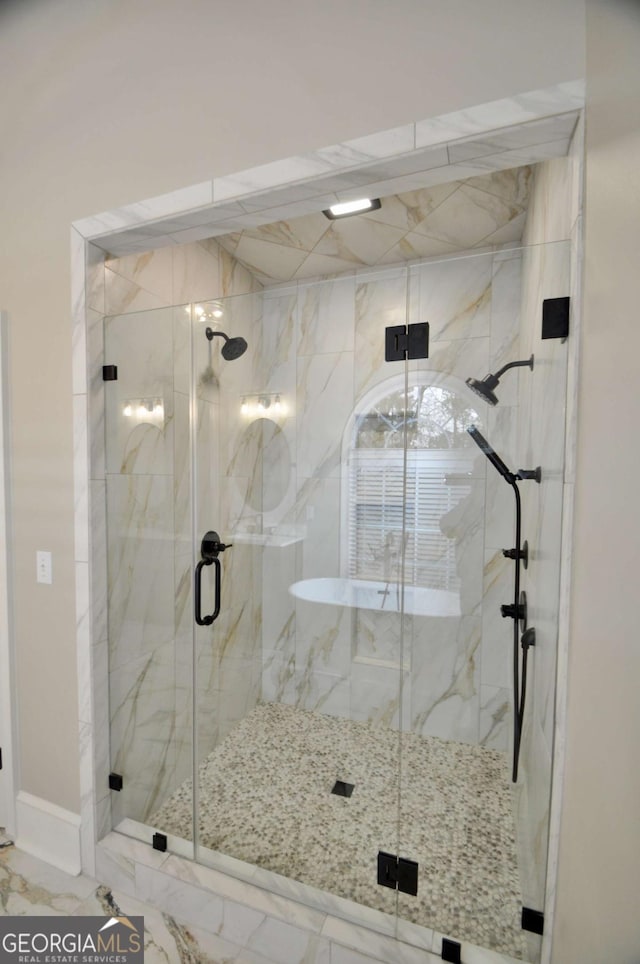 full bath with a marble finish shower and marble finish floor