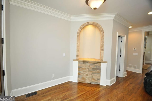 interior space featuring visible vents, ornamental molding, baseboards, and wood finished floors