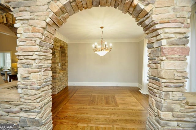 unfurnished dining area with arched walkways, light wood-style flooring, and crown molding