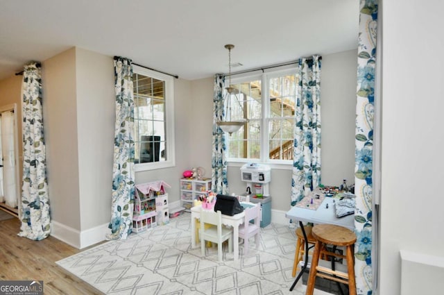 recreation room featuring wood finished floors, baseboards, and a wealth of natural light