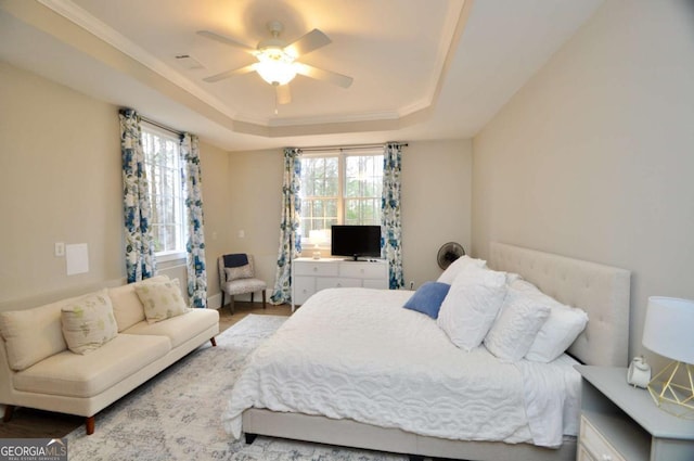 bedroom featuring multiple windows, a raised ceiling, ceiling fan, and ornamental molding