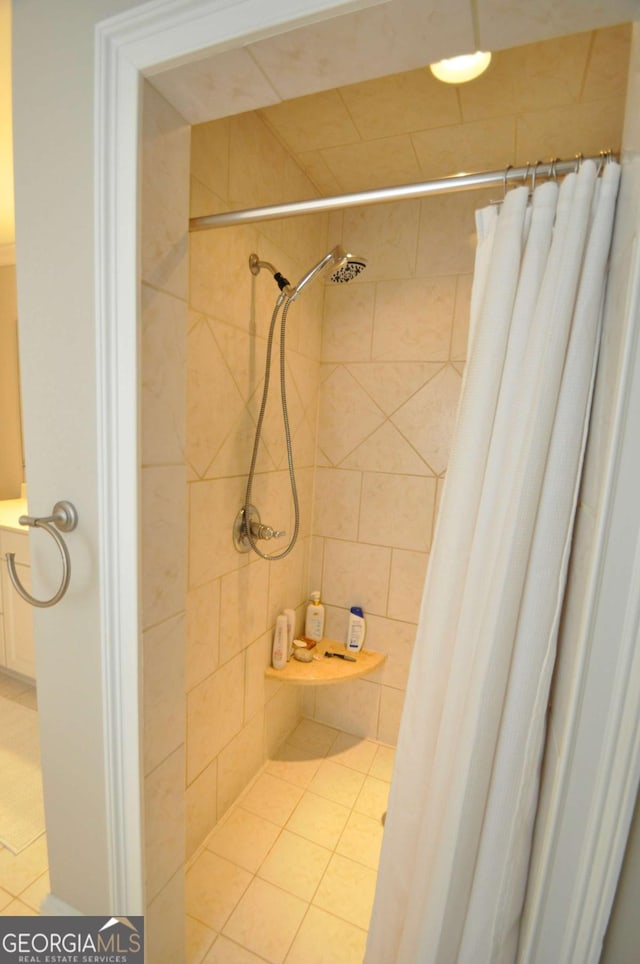 bathroom featuring tile patterned flooring and tiled shower