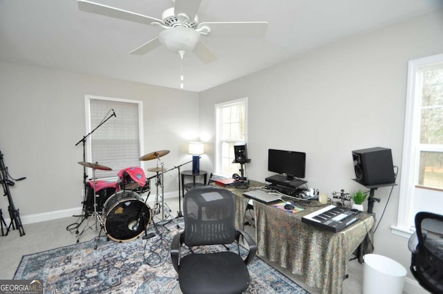 carpeted office space with a ceiling fan and baseboards