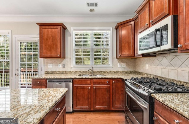 kitchen featuring visible vents, a sink, light wood-style floors, appliances with stainless steel finishes, and crown molding