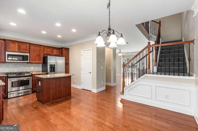 kitchen with backsplash, wood finished floors, appliances with stainless steel finishes, and a kitchen island