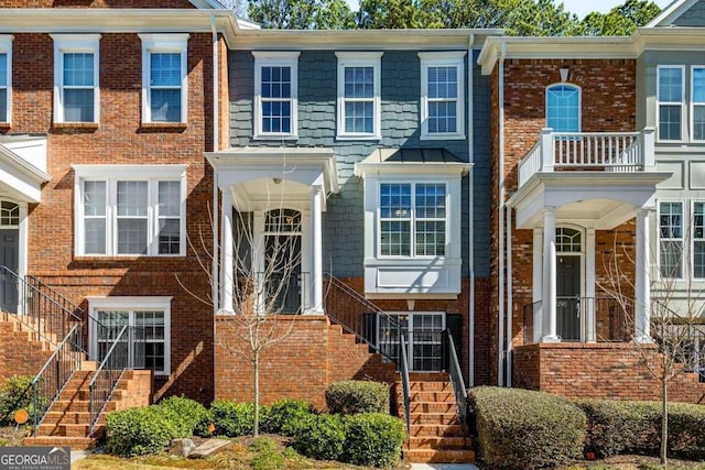 multi unit property with brick siding, stairs, and a standing seam roof