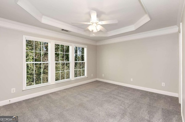 unfurnished room with visible vents, a healthy amount of sunlight, a tray ceiling, and carpet floors