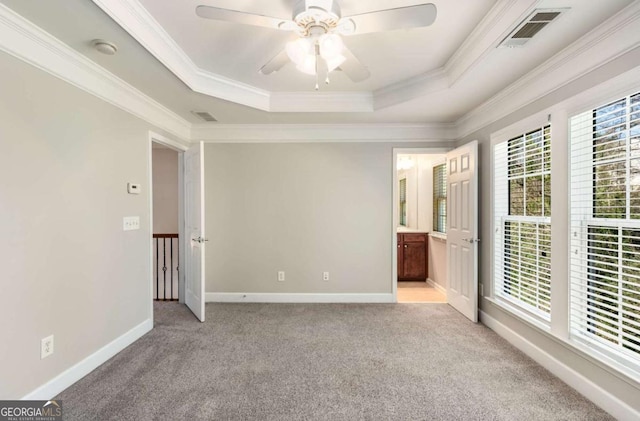 unfurnished room with visible vents, baseboards, ornamental molding, light carpet, and a raised ceiling