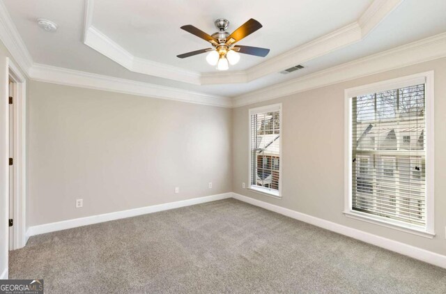 unfurnished room with visible vents, baseboards, ornamental molding, carpet floors, and a raised ceiling