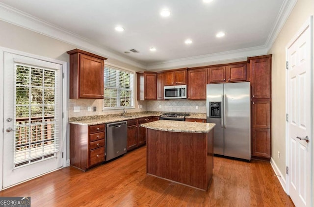 kitchen with wood finished floors, light stone countertops, stainless steel appliances, and a sink