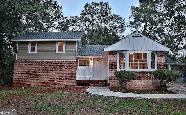 view of front facade featuring crawl space, brick siding, and roof with shingles