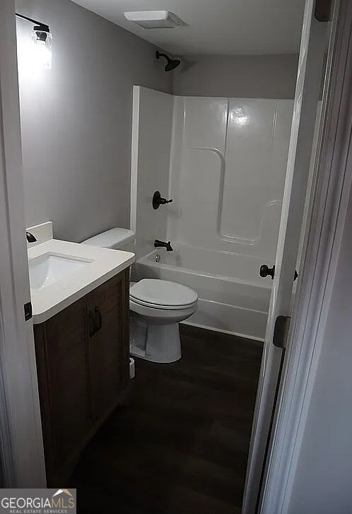 bathroom featuring visible vents, toilet, wood finished floors, bathing tub / shower combination, and vanity