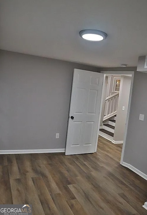 empty room with baseboards and dark wood-type flooring