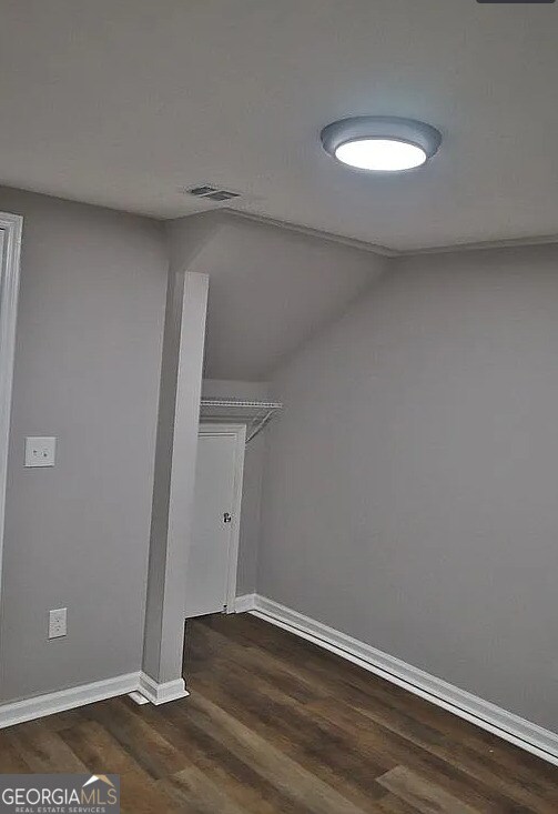 bonus room featuring dark wood-style floors, visible vents, lofted ceiling, and baseboards