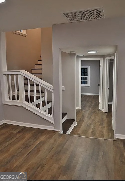 hall featuring stairs, wood finished floors, visible vents, and baseboards