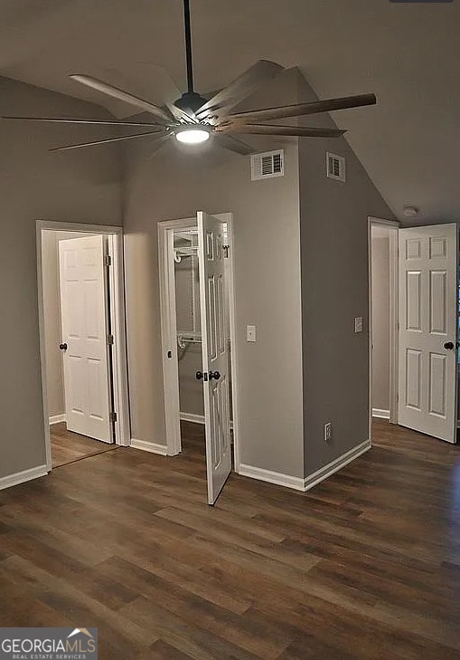 unfurnished bedroom featuring dark wood finished floors, lofted ceiling, visible vents, and a closet