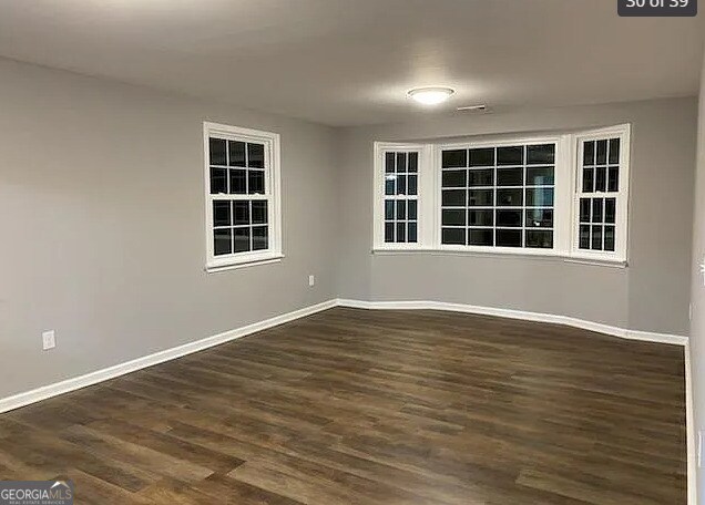 empty room featuring baseboards and dark wood-style flooring