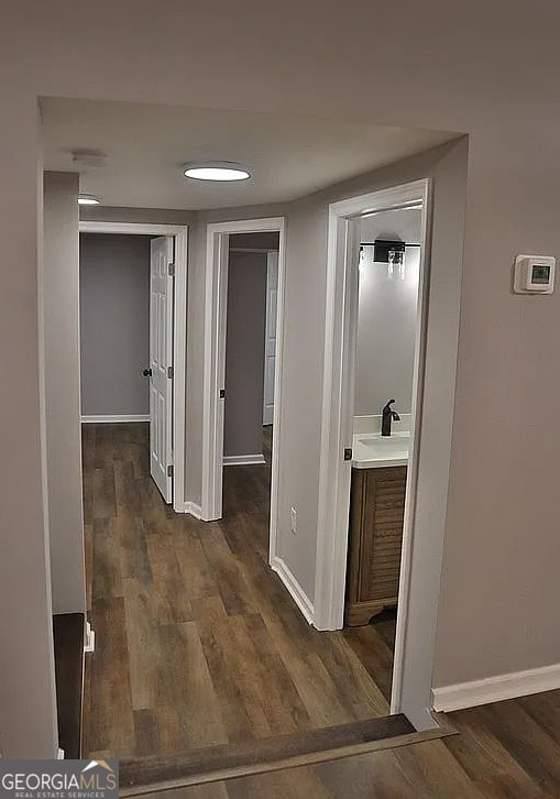 corridor featuring dark wood finished floors and baseboards