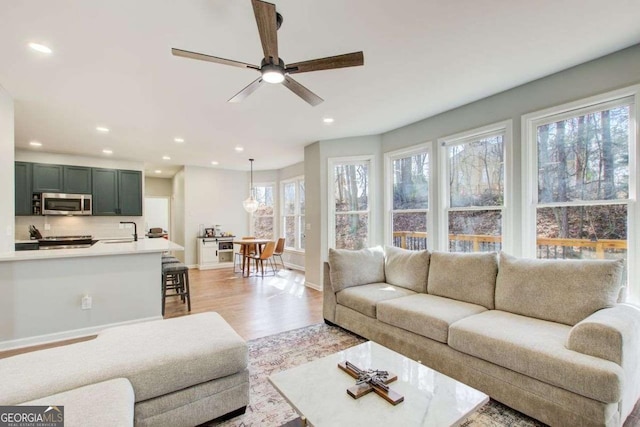 living room featuring a ceiling fan, recessed lighting, light wood-type flooring, and baseboards