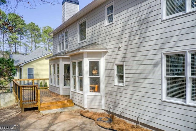 back of property featuring a wooden deck and a chimney