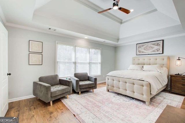 bedroom featuring visible vents, a raised ceiling, crown molding, light wood finished floors, and baseboards