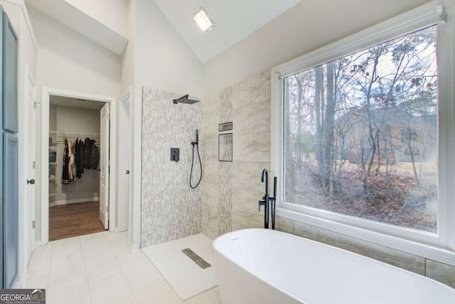 bathroom featuring vaulted ceiling, a freestanding tub, a spacious closet, and tiled shower