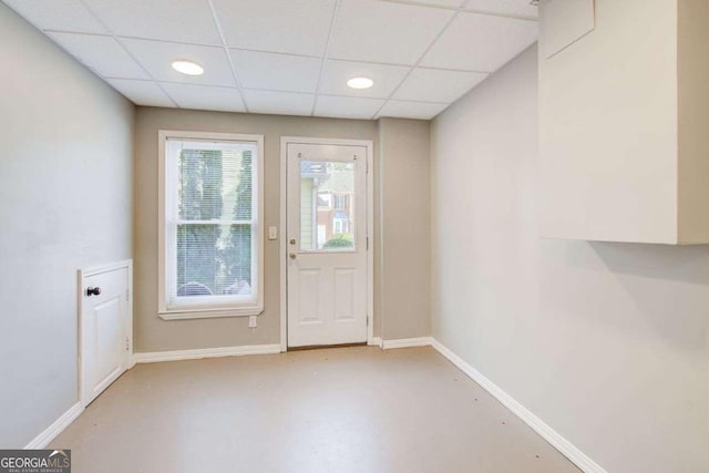 doorway to outside featuring recessed lighting, a drop ceiling, baseboards, and concrete floors